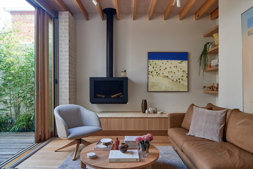 Small beach style open concept living room in Melbourne with white walls, light hardwood floors, a wood stove, a metal fireplace surround, a wall-mounted tv, brown floor and exposed beam.