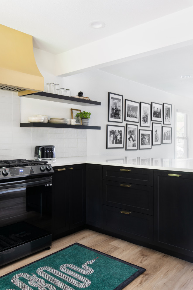 Inspiration for a mid-sized transitional u-shaped medium tone wood floor and brown floor open concept kitchen remodel in Austin with a farmhouse sink, shaker cabinets, black cabinets, quartz countertops, white backsplash, porcelain backsplash, stainless steel appliances, a peninsula and white countertops