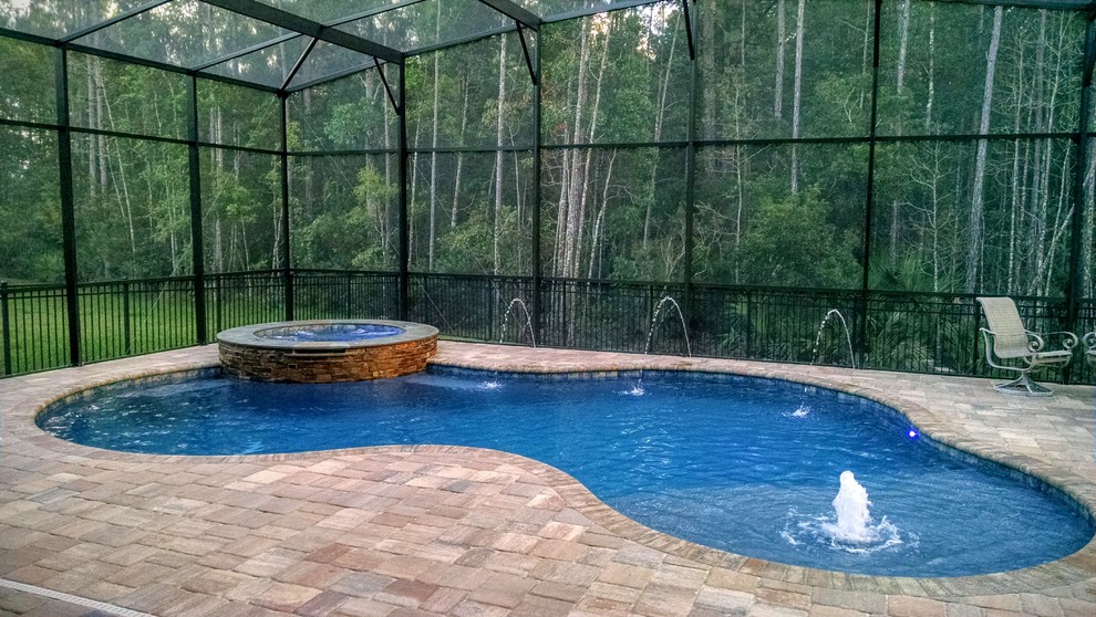 This is an example of a mid-sized country backyard custom-shaped pool in Jacksonville with concrete pavers.