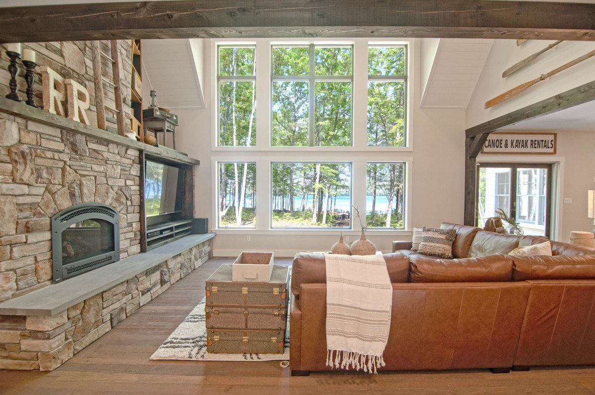 Photo of a large arts and crafts open concept living room in Portland Maine with grey walls, medium hardwood floors, a standard fireplace, a stone fireplace surround, a built-in media wall and brown floor.