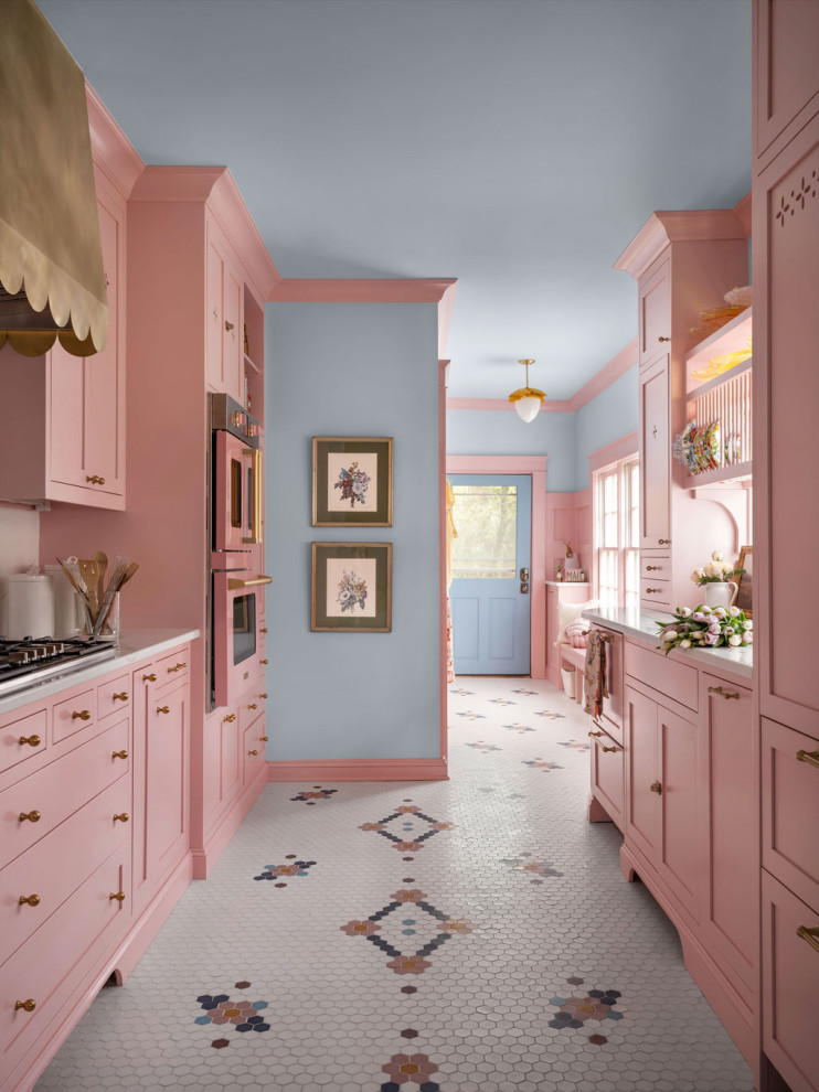 Diseño de cocina bohemia sin isla con armarios estilo shaker, puertas de armarios rosa, electrodomésticos de colores, suelo multicolor y encimeras blancas