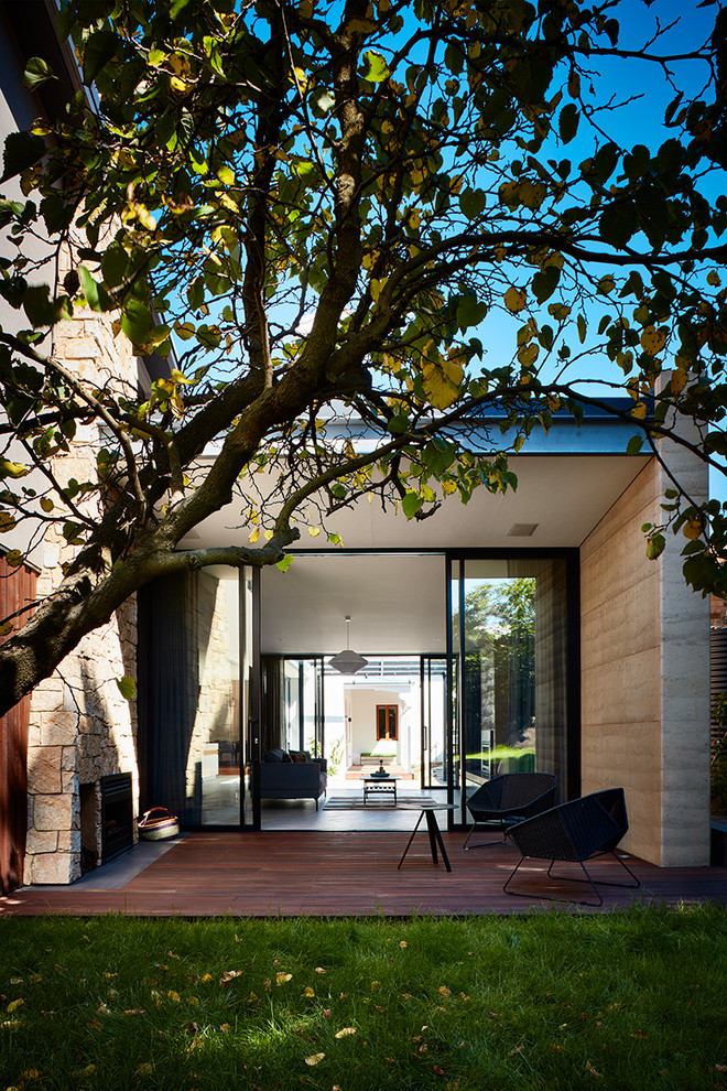 This is an example of a contemporary backyard deck in Melbourne with a fire feature and a roof extension.