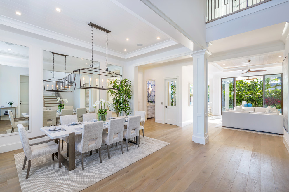 Beach style dining room in Miami with white walls, medium hardwood floors and brown floor.