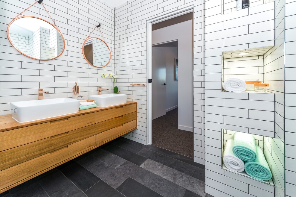 Large contemporary master bathroom in Melbourne with beaded inset cabinets, light wood cabinets, a freestanding tub, a double shower, a wall-mount toilet, gray tile, subway tile, white walls, ceramic floors, a vessel sink and wood benchtops.