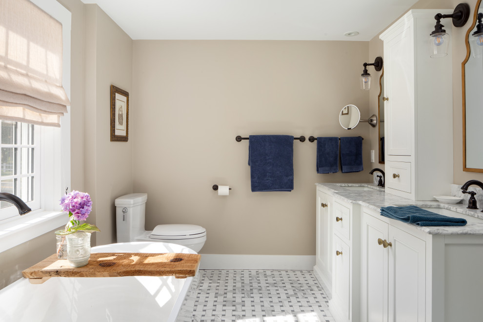 Mid-sized transitional master bathroom in Providence with shaker cabinets, white cabinets, a freestanding tub, a two-piece toilet, beige walls, ceramic floors, an undermount sink, grey floor and grey benchtops.