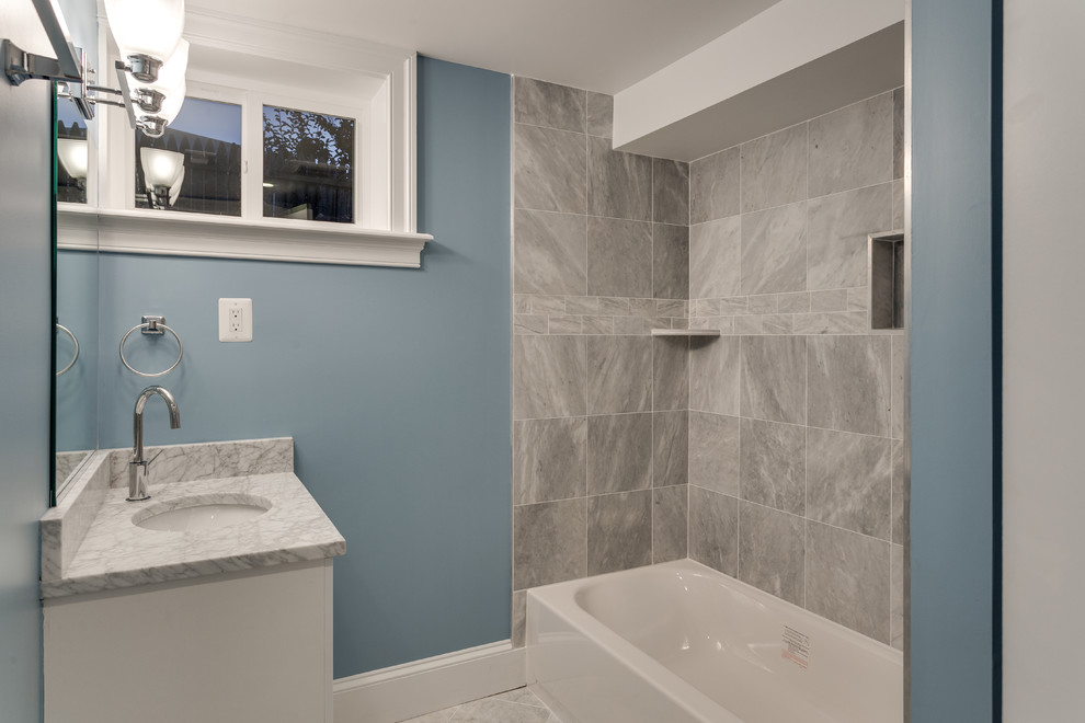 Example of a small transitional 3/4 gray tile and marble tile marble floor and gray floor tub/shower combo design in Baltimore with white cabinets, an undermount tub, blue walls, an undermount sink, marble countertops, flat-panel cabinets and white countertops