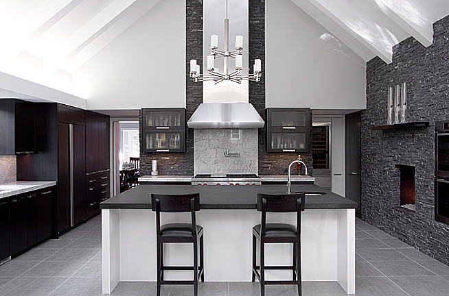 Inspiration for a large modern l-shaped open plan kitchen in Kansas City with an undermount sink, flat-panel cabinets, dark wood cabinets, onyx benchtops, grey splashback, stone tile splashback, stainless steel appliances, porcelain floors and with island.