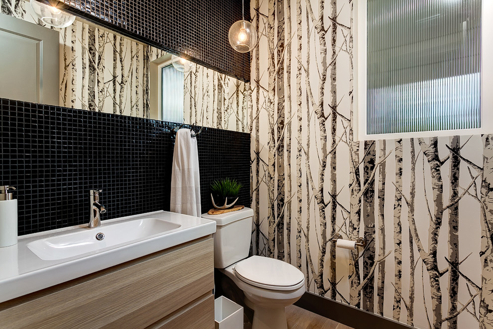 Inspiration for a small transitional 3/4 bathroom in Boise with flat-panel cabinets, light wood cabinets, black tile, mosaic tile, light hardwood floors, a two-piece toilet and an integrated sink.