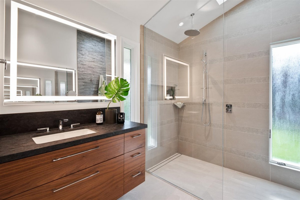 Photo of a mid-sized midcentury master bathroom in San Francisco with flat-panel cabinets, medium wood cabinets, a curbless shower, a one-piece toilet, gray tile, stone tile, grey walls, porcelain floors, an undermount sink, engineered quartz benchtops, grey floor, an open shower, grey benchtops, a double vanity, a built-in vanity and vaulted.