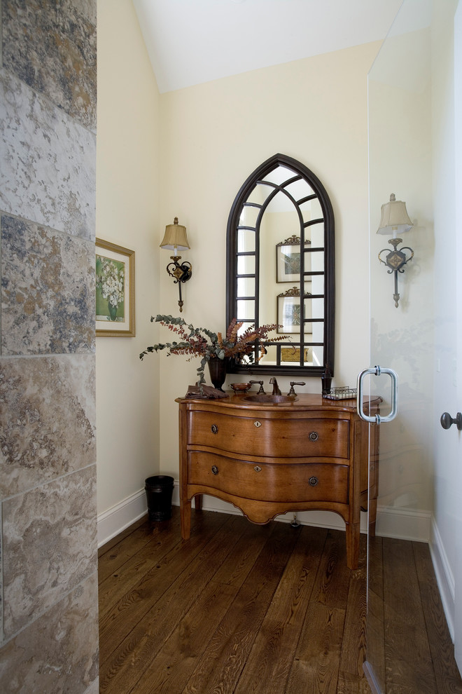 This is an example of a large traditional powder room in Chicago with furniture-like cabinets, medium wood cabinets, beige walls, medium hardwood floors, an undermount sink and wood benchtops.