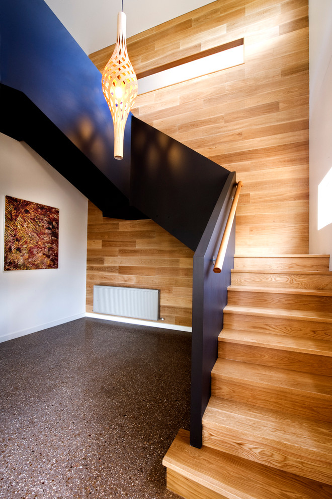 This is an example of a large contemporary wood u-shaped staircase in Melbourne with wood risers.