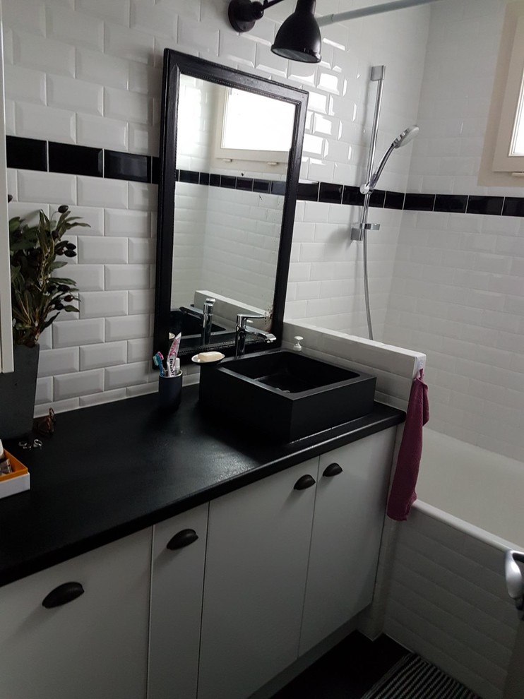 Photo of a small midcentury master bathroom in Paris with flat-panel cabinets, white cabinets, a drop-in tub, white tile, subway tile, vinyl floors, a vessel sink, laminate benchtops, black floor and black benchtops.