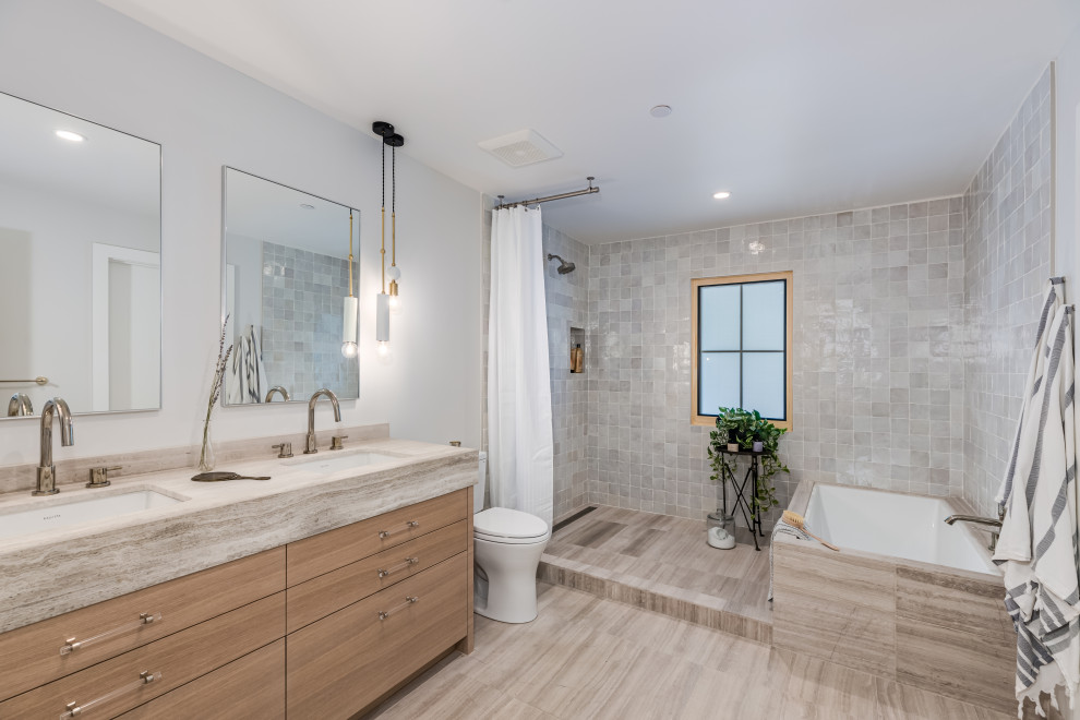 Traditional wet room bathroom in Orange County with flat-panel cabinets, medium wood cabinets, a submerged bath, grey tiles, white walls, a submerged sink, grey floors, a shower curtain, grey worktops, a wall niche, double sinks and a built in vanity unit.