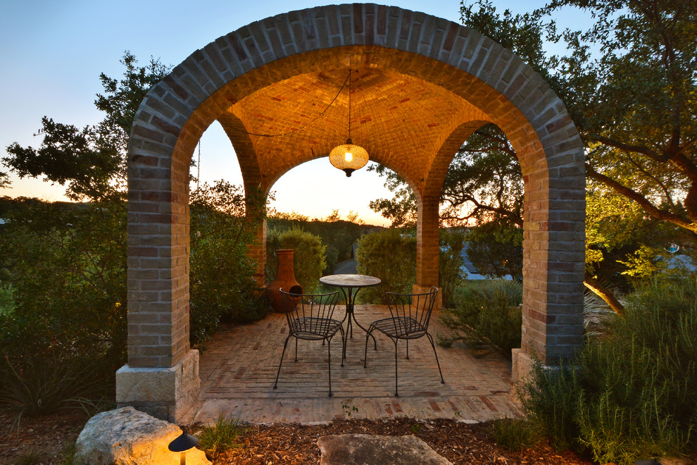 This is an example of a mediterranean patio in Austin with brick pavers and a gazebo/cabana.