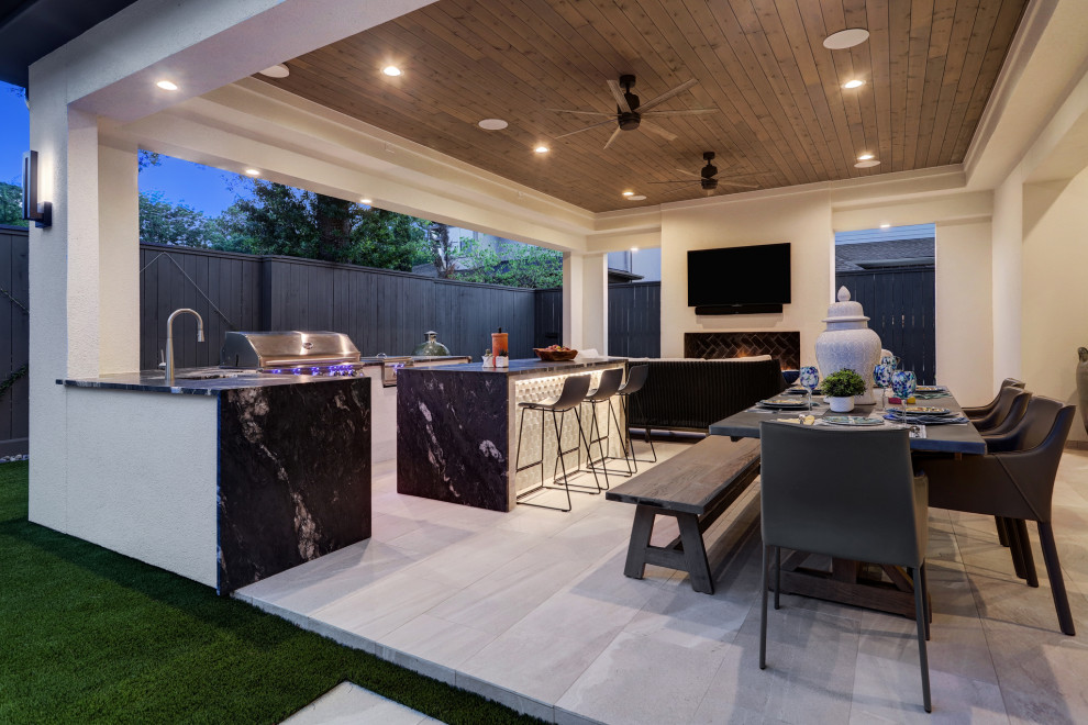 Large modern backyard patio in Houston with with fireplace, tile and a roof extension.