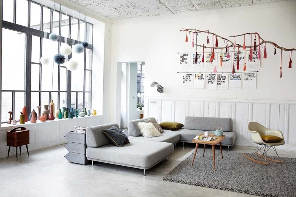 Large industrial enclosed family room in Lille with white walls and concrete floors.