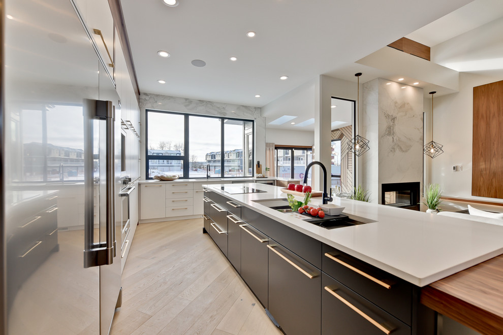 This is an example of a large contemporary eat-in kitchen in Edmonton with an undermount sink, flat-panel cabinets, medium wood cabinets, quartz benchtops, grey splashback, marble splashback, stainless steel appliances, light hardwood floors and with island.