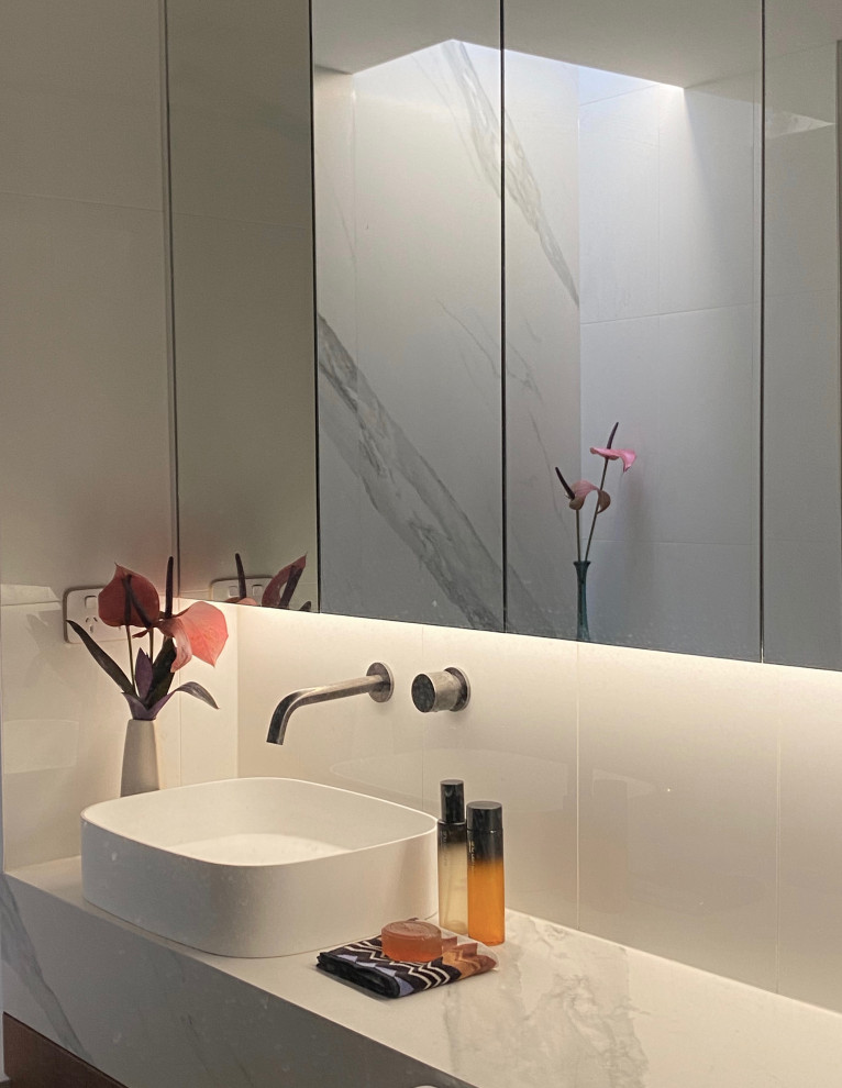 This is an example of a mid-sized contemporary master bathroom in Melbourne with white cabinets, a drop-in tub, an open shower, a one-piece toilet, white tile, stone slab, white walls, cement tiles, a vessel sink, engineered quartz benchtops, grey floor, a single vanity, a built-in vanity and decorative wall panelling.