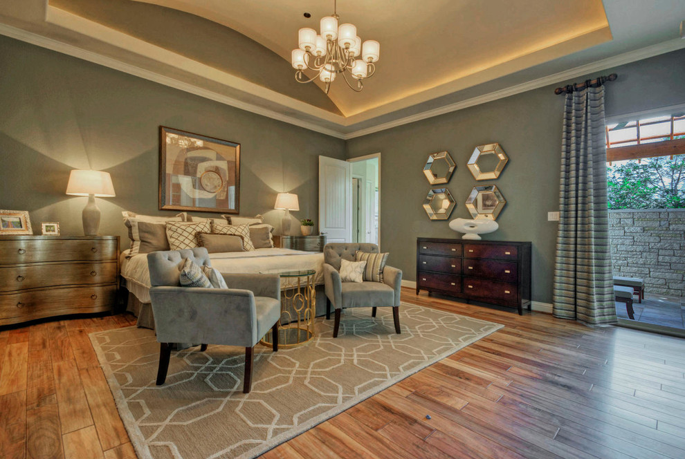 This is an example of a large traditional master bedroom in Austin with grey walls and medium hardwood floors.