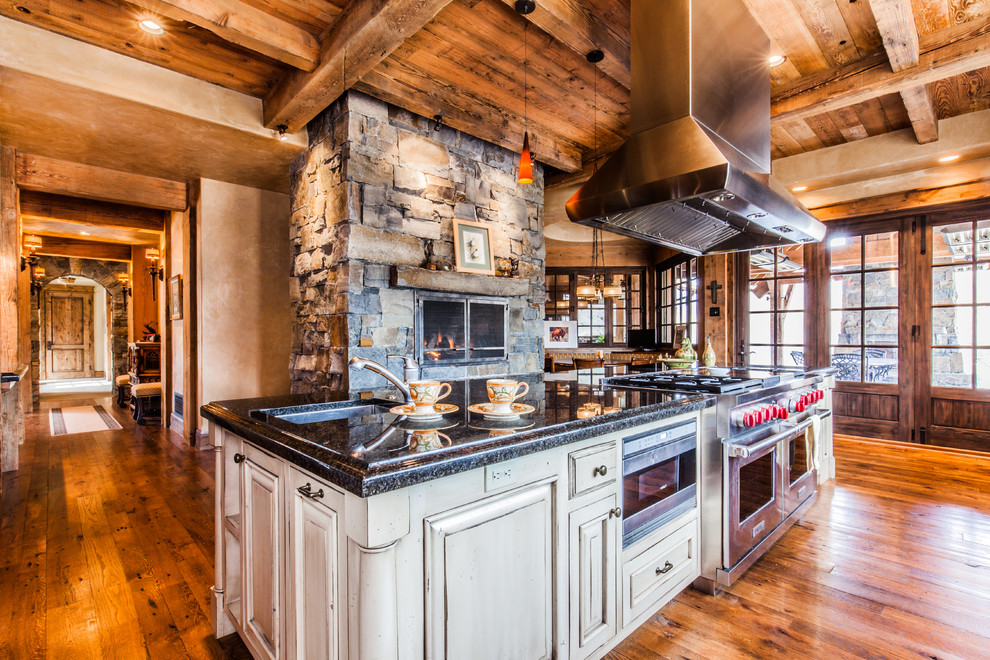 Eat-in kitchen - large rustic single-wall dark wood floor eat-in kitchen idea with an undermount sink, raised-panel cabinets, dark wood cabinets, granite countertops, stainless steel appliances and an island
