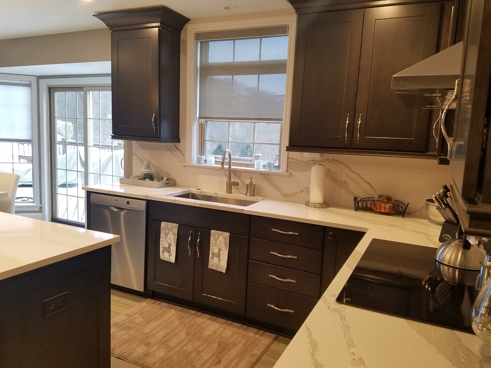 Inspiration for a mid-sized transitional l-shaped porcelain tile and gray floor enclosed kitchen remodel with an undermount sink, raised-panel cabinets, dark wood cabinets, quartz countertops, white backsplash, stone slab backsplash, stainless steel appliances and an island