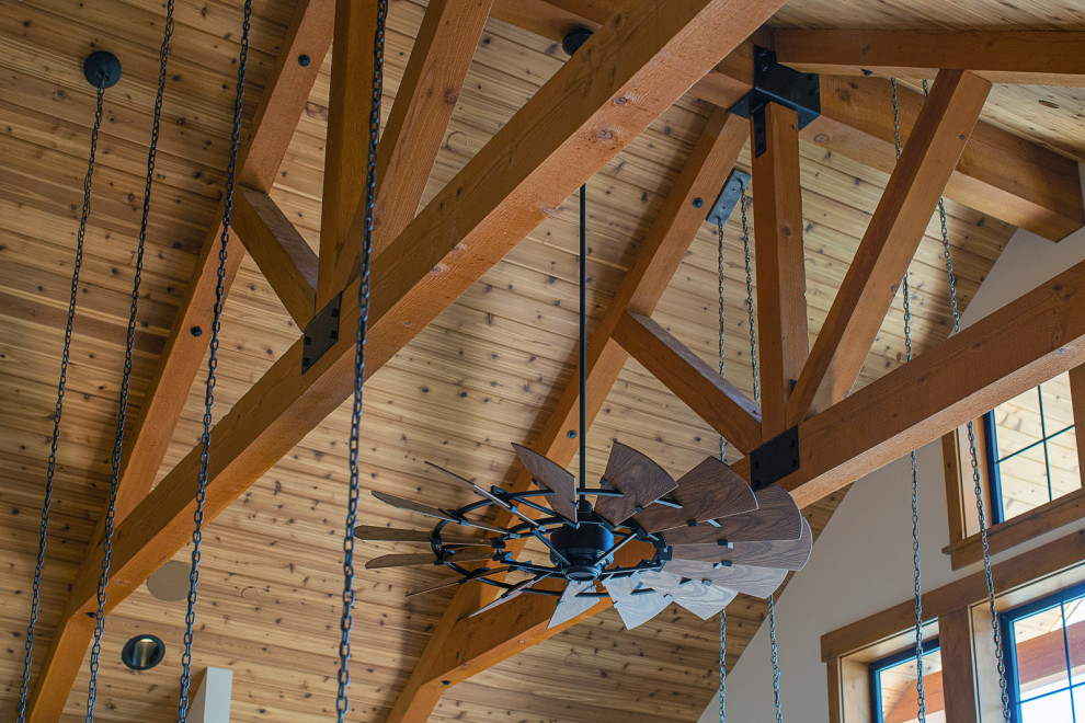 Great room - large rustic medium tone wood floor, brown floor, exposed beam and wood wall great room idea in Seattle with white walls, a two-sided fireplace and a stacked stone fireplace
