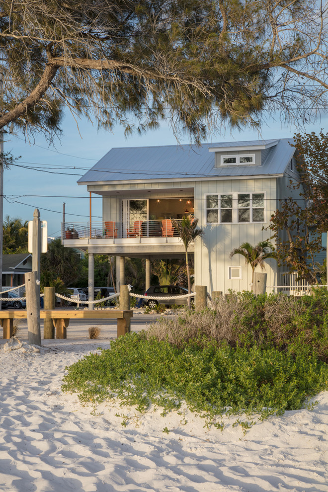 This is an example of a small beach style two-storey grey house exterior in Tampa with concrete fiberboard siding, a gable roof and a metal roof.
