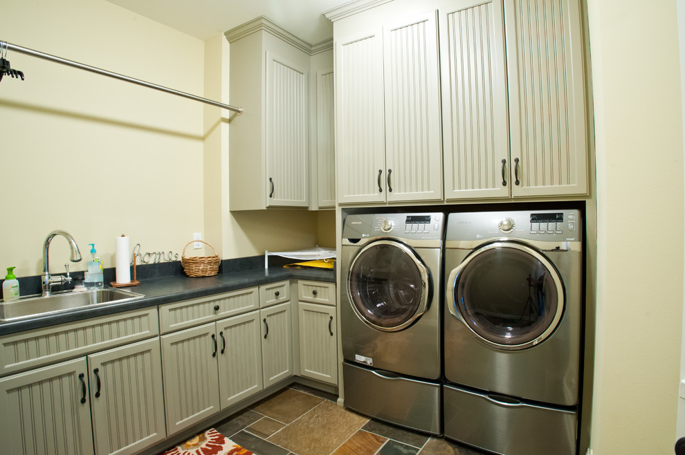 Mid-sized traditional l-shaped dedicated laundry room in Milwaukee with a drop-in sink, grey cabinets, laminate benchtops, beige walls, ceramic floors and a side-by-side washer and dryer.