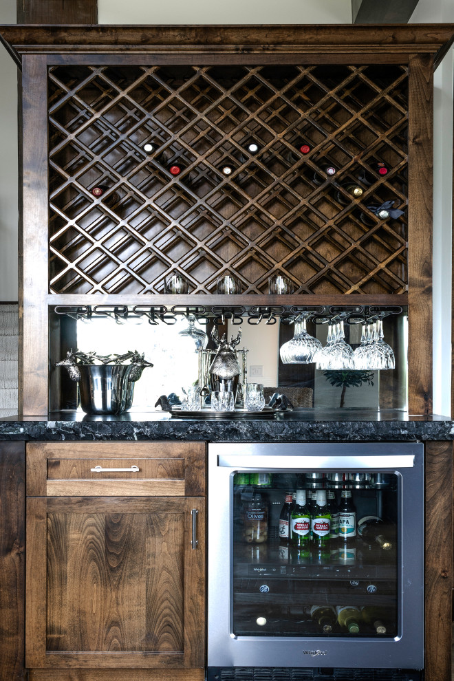 Inspiration for a large traditional u-shaped home bar in Sacramento with shaker cabinets, medium wood cabinets, granite benchtops, black splashback, granite splashback, medium hardwood floors, brown floor and black benchtop.