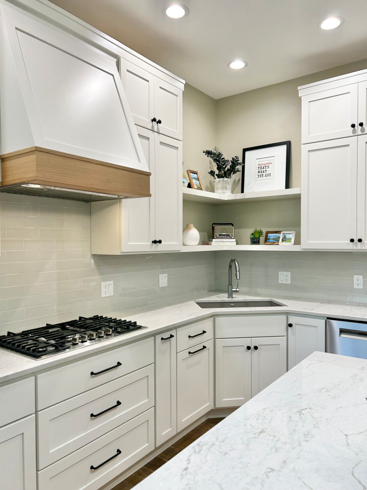 Open concept kitchen - mid-sized transitional l-shaped medium tone wood floor and brown floor open concept kitchen idea with an undermount sink, flat-panel cabinets, white cabinets, quartz countertops, gray backsplash, ceramic backsplash, stainless steel appliances, an island and white countertops