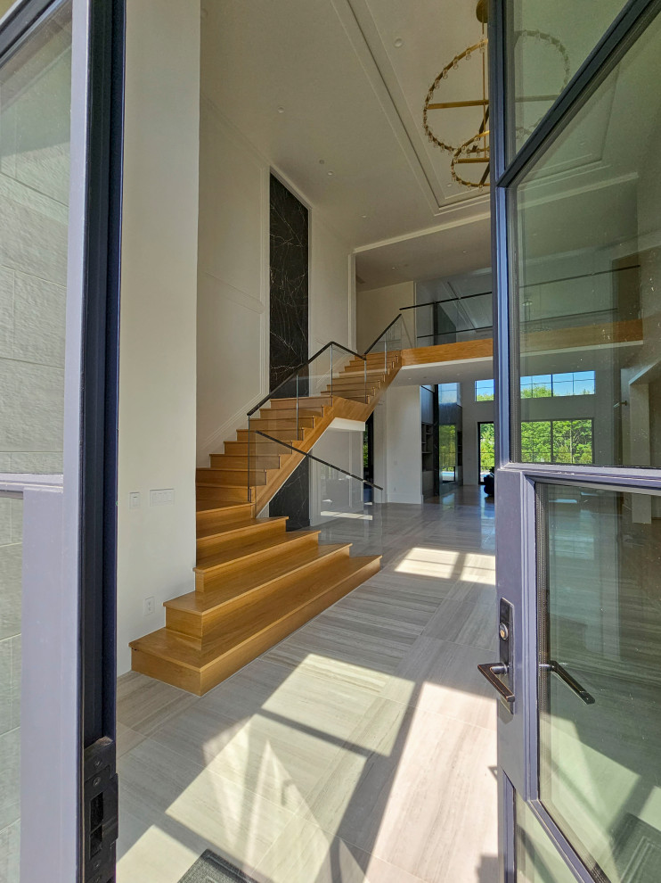 Photo of an expansive contemporary wood floating mixed railing staircase in DC Metro with wood risers and wainscoting.