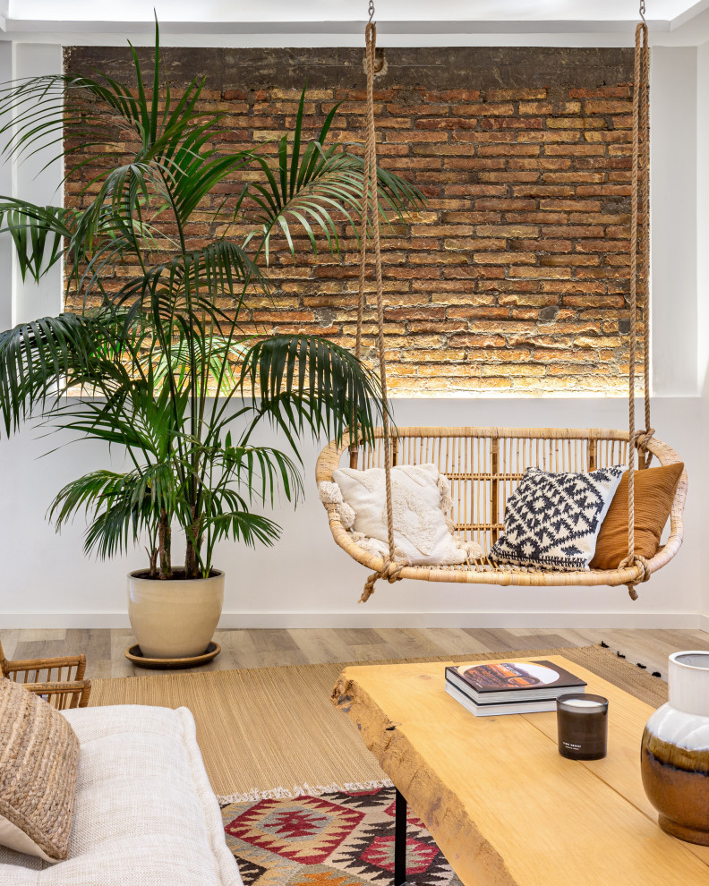 Inspiration for a tropical living room in Other with white walls, medium hardwood floors, brown floor and brick walls.