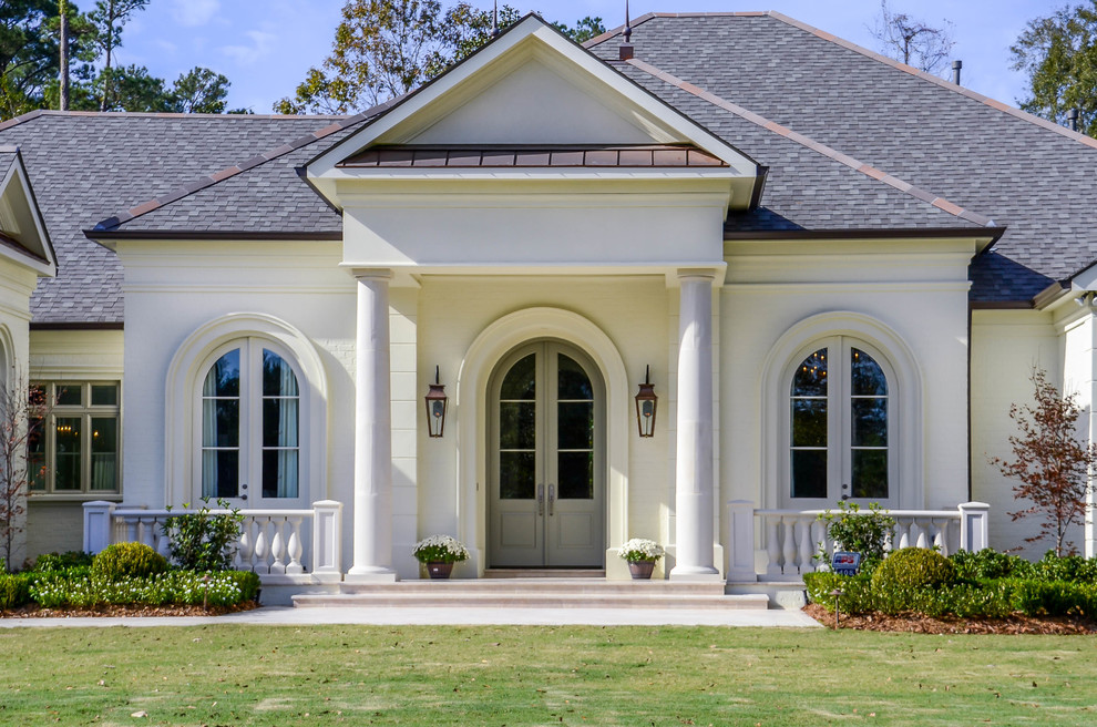 Large traditional one-storey white exterior in New Orleans with stone veneer and a gable roof.