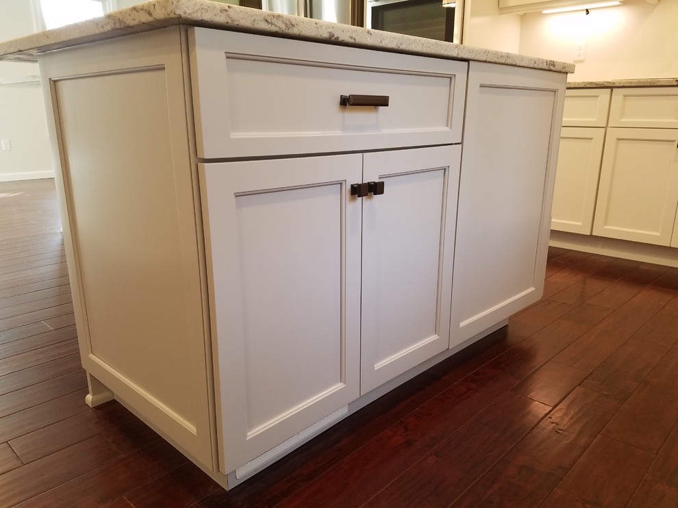Eat-in kitchen - mid-sized transitional l-shaped dark wood floor and brown floor eat-in kitchen idea with a farmhouse sink, shaker cabinets, white cabinets, granite countertops, white backsplash, subway tile backsplash, stainless steel appliances and an island