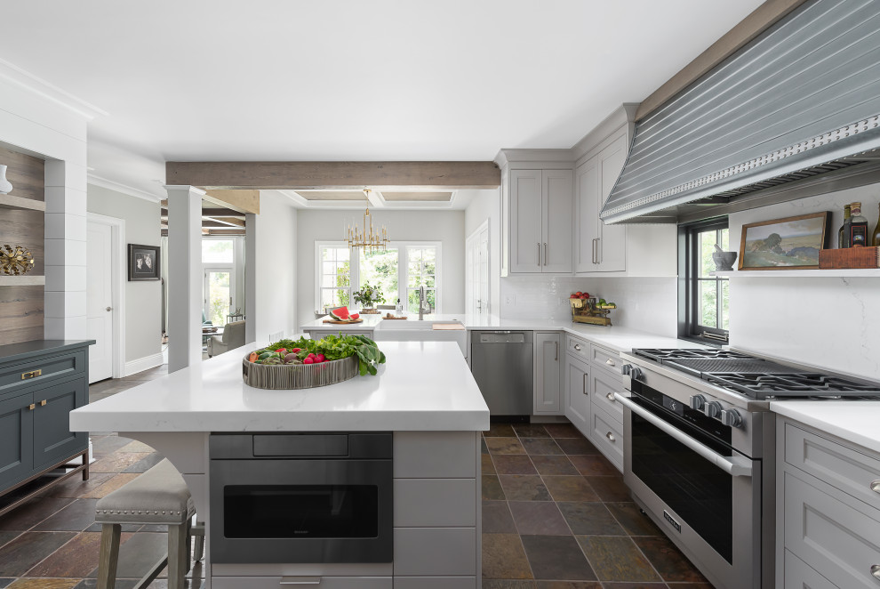 Design ideas for a transitional eat-in kitchen in Chicago with a farmhouse sink, shaker cabinets, grey cabinets, white splashback, stainless steel appliances, slate floors, with island, brown floor, white benchtop, quartz benchtops and subway tile splashback.