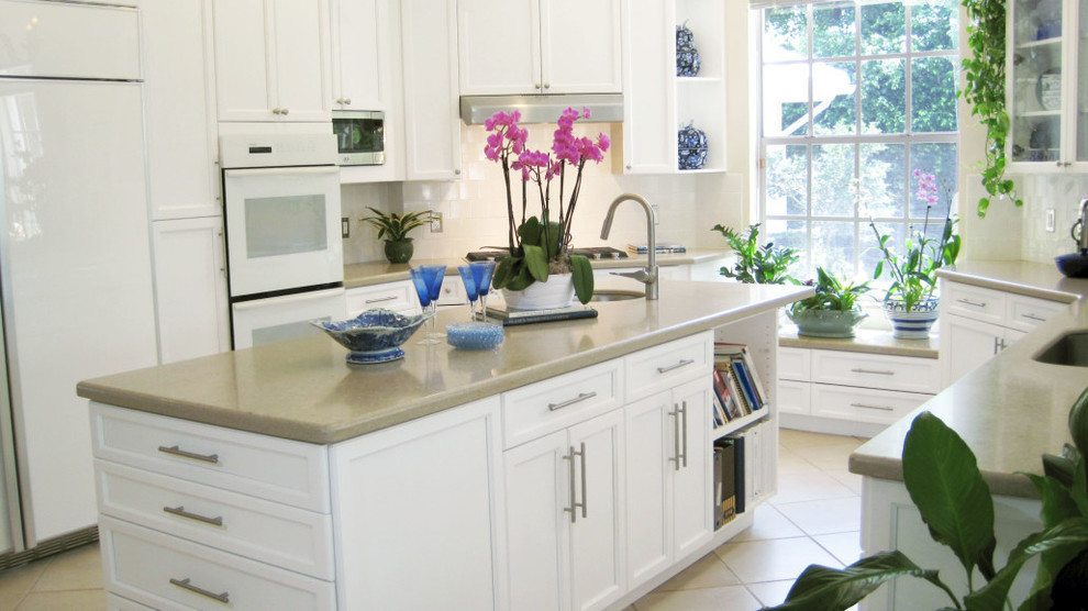 Inspiration for a large transitional u-shaped eat-in kitchen in Miami with an undermount sink, shaker cabinets, white cabinets, white splashback, white appliances, ceramic floors, with island, quartz benchtops and ceramic splashback.