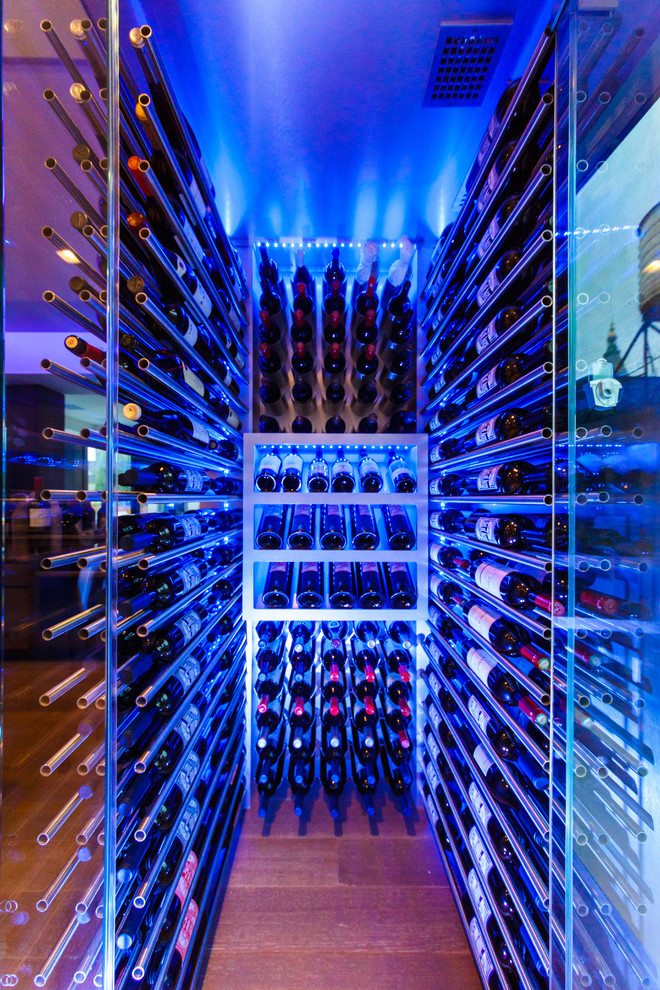Photo of a small modern wine cellar in New York with light hardwood floors and display racks.
