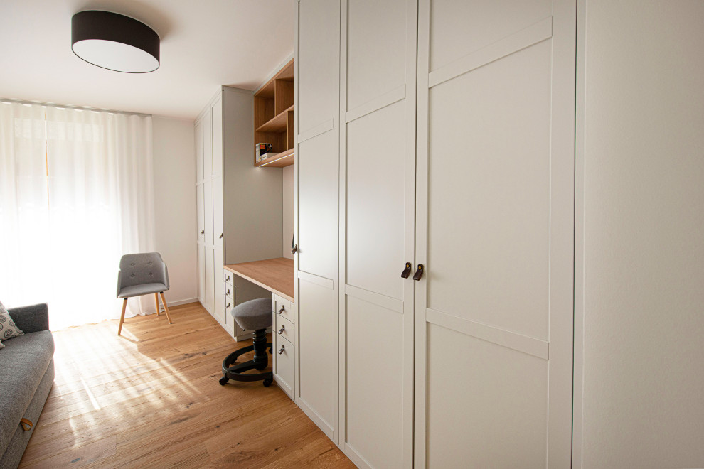 Mittelgroßes Modernes Ankleidezimmer mit Kassettenfronten, weißen Schränken, gebeiztem Holzboden und braunem Boden in Sonstige
