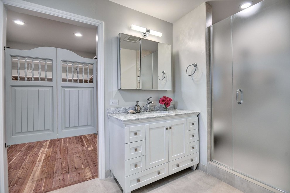 This is an example of an expansive contemporary master bathroom in San Francisco with furniture-like cabinets, white cabinets, a drop-in tub, an open shower, a one-piece toilet, gray tile, purple walls, linoleum floors, a drop-in sink, granite benchtops, grey floor and a hinged shower door.