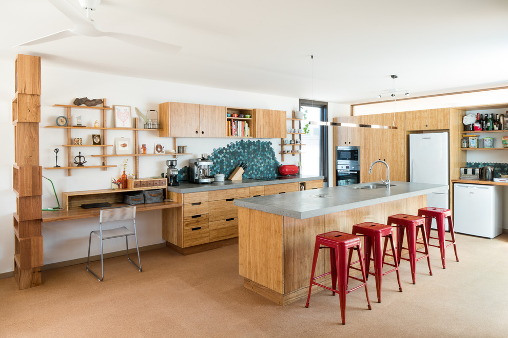 Design ideas for a mid-sized contemporary u-shaped open plan kitchen in Melbourne with an undermount sink, flat-panel cabinets, light wood cabinets, concrete benchtops, green splashback, stone tile splashback, cork floors, with island and beige floor.