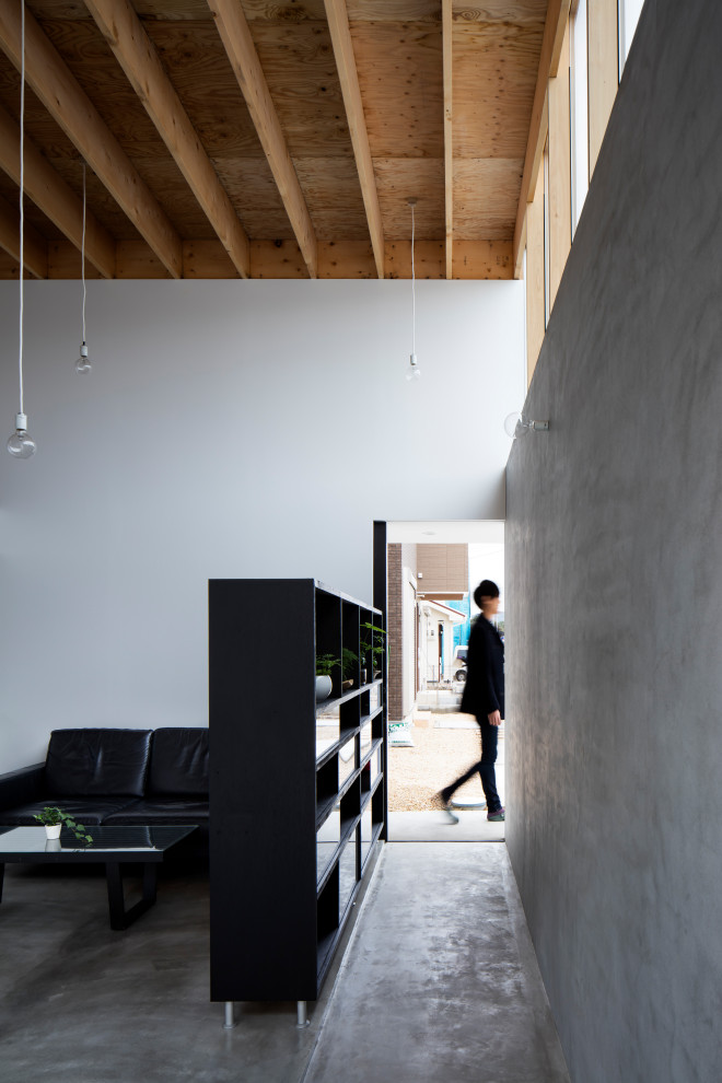 Cette photo montre une entrée industrielle avec un mur gris, sol en béton ciré, une porte coulissante, une porte noire, un sol gris et un plafond en bois.