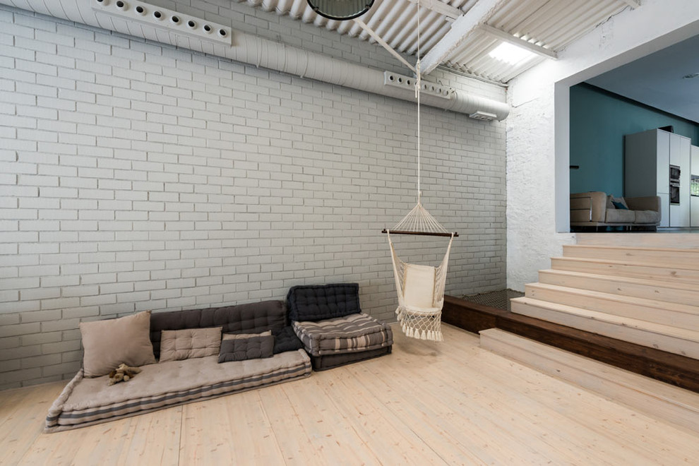 Imagen de sala de estar tipo loft urbana grande sin chimenea con paredes grises, suelo de madera clara, televisor independiente y suelo beige