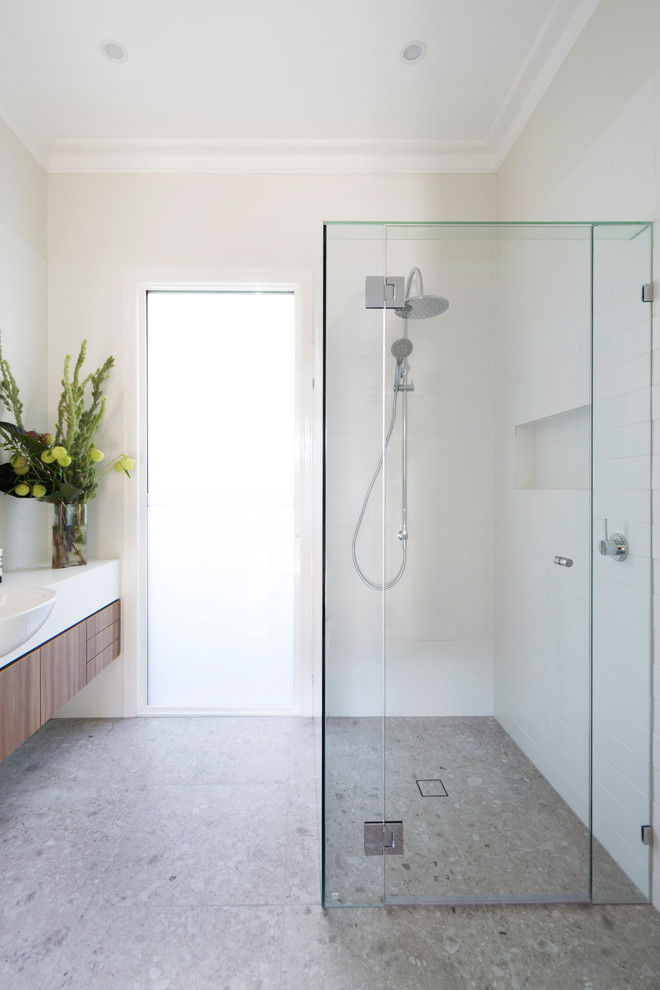 This is an example of a mid-sized contemporary 3/4 bathroom in Melbourne with medium wood cabinets, white tile, porcelain tile, white walls, porcelain floors, engineered quartz benchtops, beige floor, a hinged shower door, white benchtops, flat-panel cabinets, a corner shower and a drop-in sink.