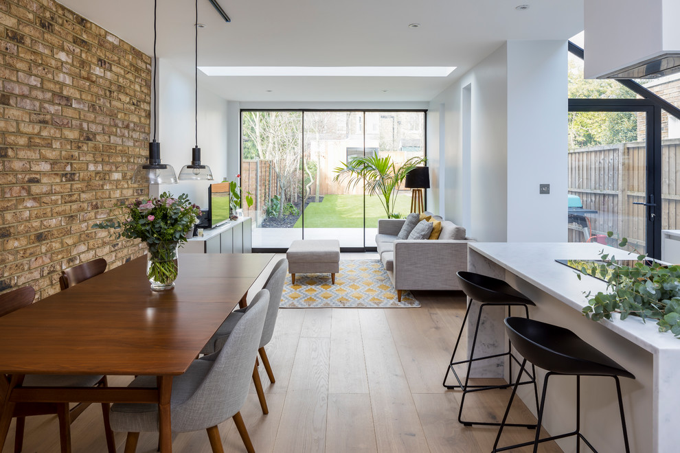 This is an example of a mid-sized contemporary open plan dining in London with red walls, medium hardwood floors and brown floor.