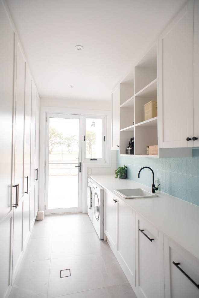 Design ideas for a large modern galley dedicated laundry room in Sydney with a drop-in sink, shaker cabinets, white cabinets, quartz benchtops, blue splashback, ceramic splashback, blue walls, ceramic floors, a side-by-side washer and dryer, grey floor and white benchtop.