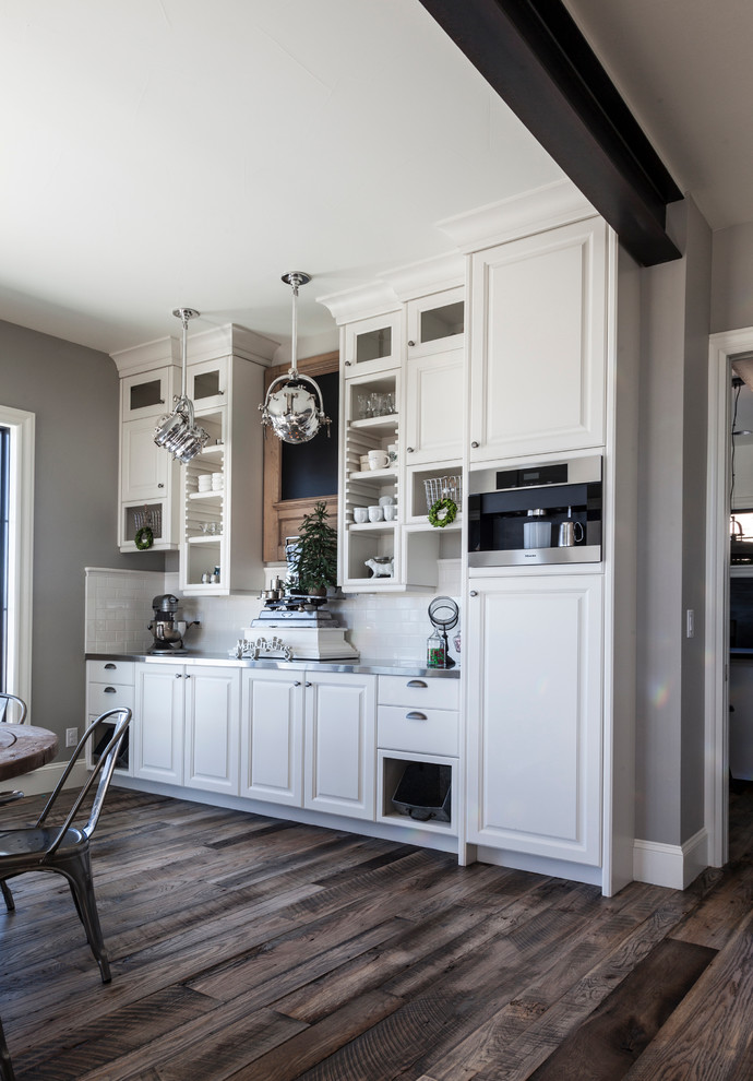 Home design - transitional medium tone wood floor home design idea in Denver with a farmhouse sink, raised-panel cabinets, white cabinets, soapstone countertops, white backsplash, subway tile backsplash, stainless steel appliances and an island