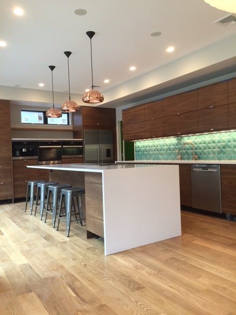 This is an example of a modern kitchen in New York with a double-bowl sink, flat-panel cabinets, light wood cabinets, quartzite benchtops, light hardwood floors and with island.