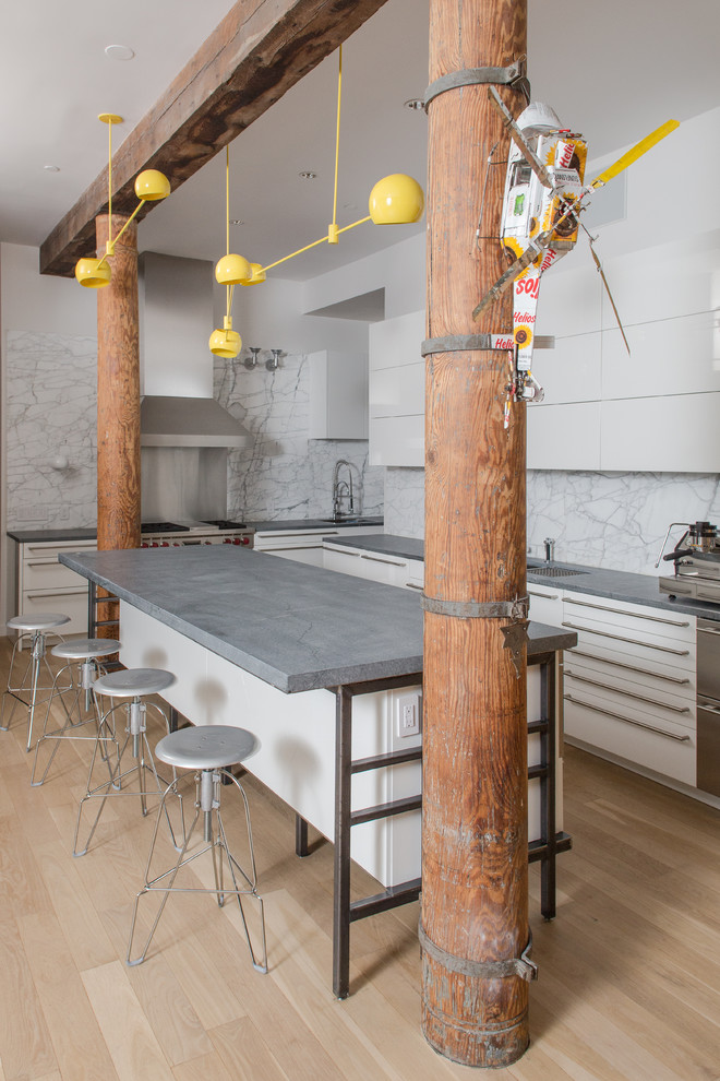 Inspiration for an industrial l-shaped kitchen in New York with flat-panel cabinets, white cabinets, white splashback, stainless steel appliances, light hardwood floors and with island.
