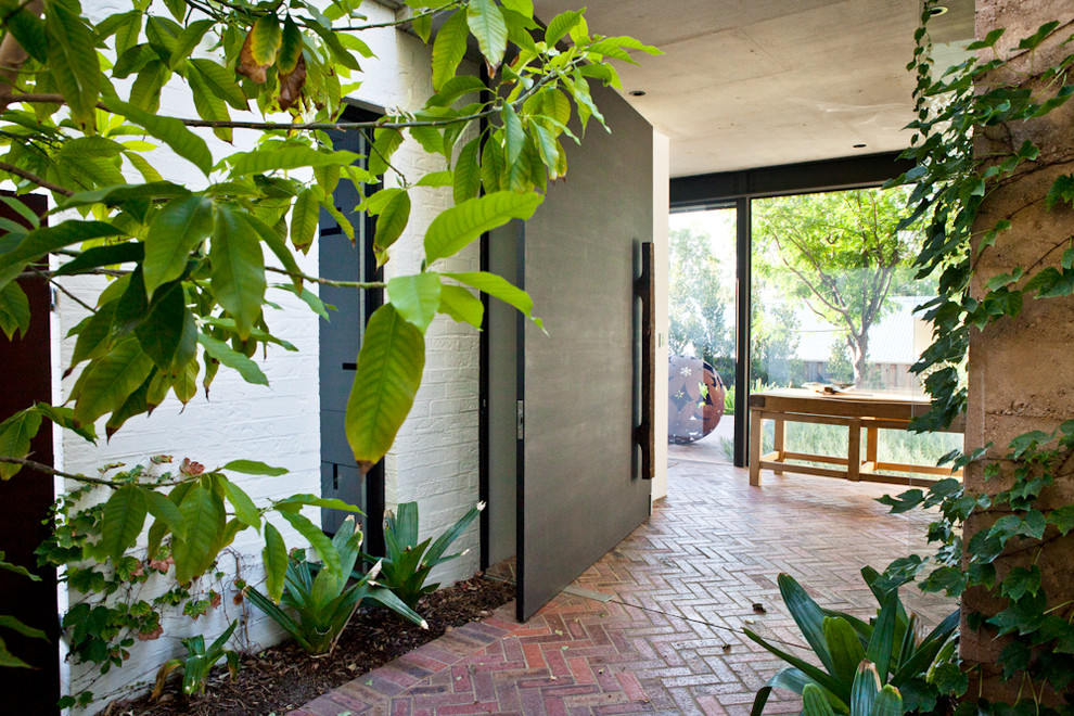 Inspiration for a contemporary front door in Perth with a pivot front door, brick floors and red floor.