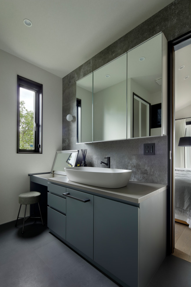 Aménagement d'un WC et toilettes contemporain avec des portes de placard grises, un carrelage gris, un plan de toilette gris et meuble-lavabo encastré.